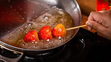 La fruta se clava en un pincho de madera y se "baña" en el ardiente caramelo, obteniendo una textura crocante, de "cristal".