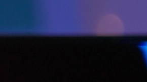 Mujer con auriculares frente a una pantalla iluminada se frota los ojos por fatiga visual causada por el uso prolongado de computadoras.