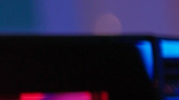 Mujer con auriculares frente a una pantalla iluminada se frota los ojos por fatiga visual causada por el uso prolongado de computadoras.