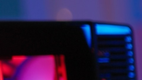 Mujer con auriculares frente a una pantalla iluminada se frota los ojos por fatiga visual causada por el uso prolongado de computadoras.