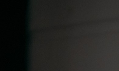 Mujer joven con guantes de hule amarillos limpiando la ventana de su hogar con un spray limpiador