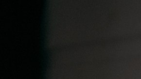 Mujer joven con guantes de hule amarillos limpiando la ventana de su hogar con un spray limpiador