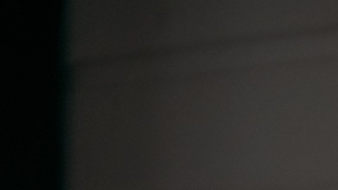 Mujer joven con guantes de hule amarillos limpiando la ventana de su hogar con un spray limpiador