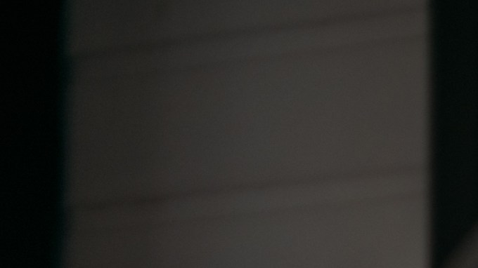 Mujer joven con guantes de hule amarillos limpiando la ventana de su hogar con un spray limpiador