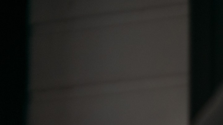 Mujer joven con guantes de hule amarillos limpiando la ventana de su hogar con un spray limpiador